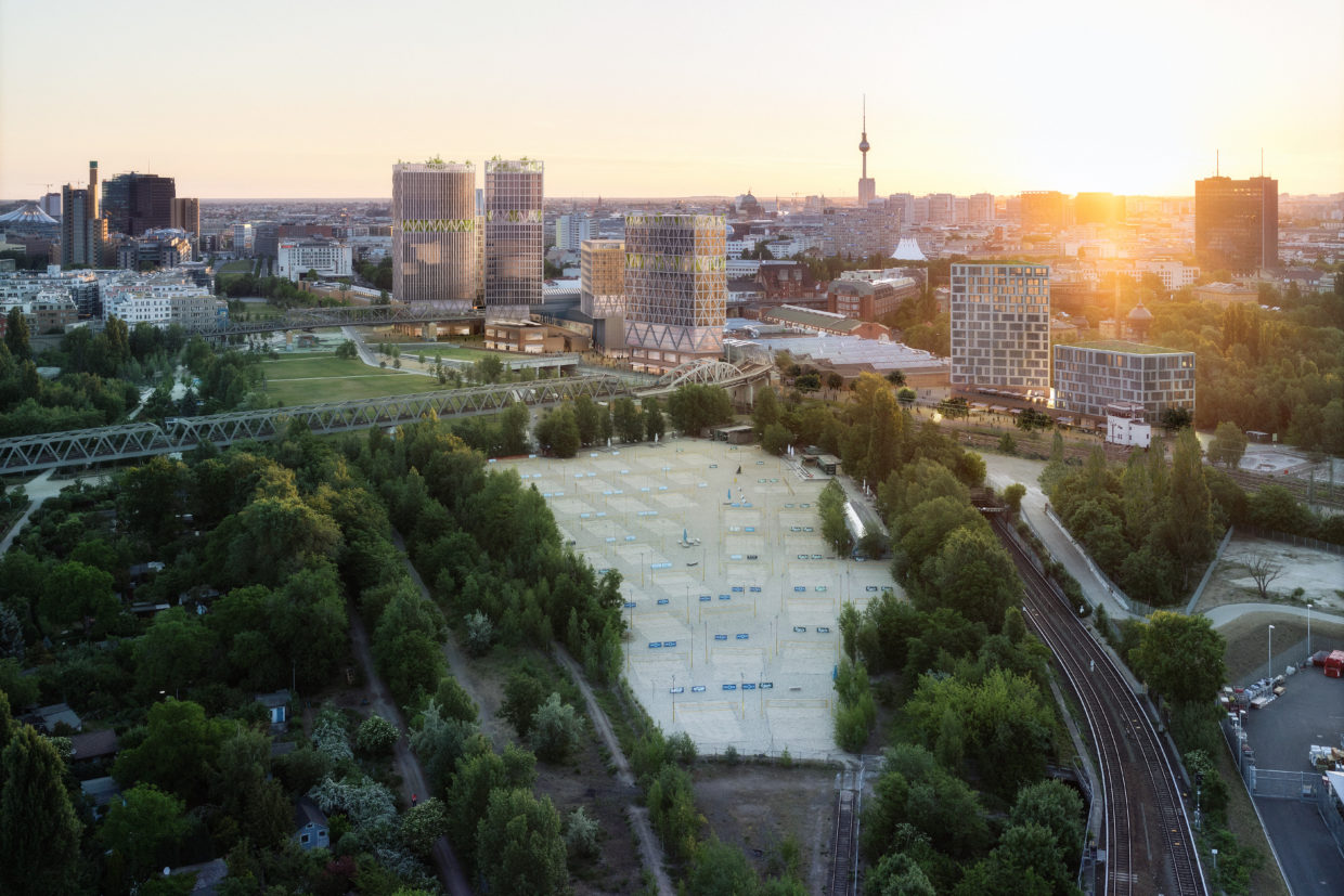 Aerial shot of Berlin at dawn with new buildings surrounded by a park besides rails, TV tower in the back.