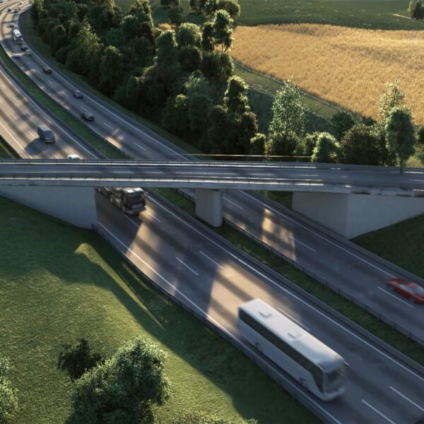Bridge over motorway between trees, meadows and fields on sunny day with cars, bus and trucks driving fast.