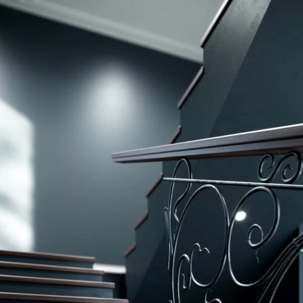 Staircase painted in dark grey with an old fashioned black railing. Sun shines through a window.