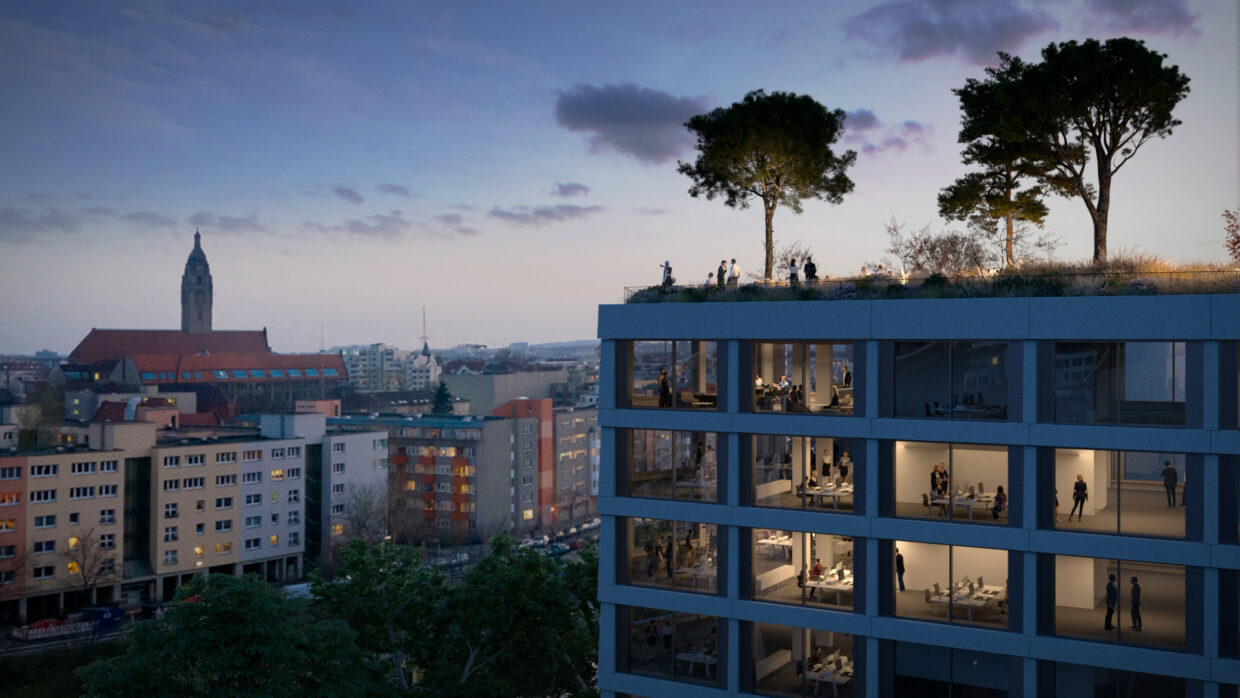 Office building with large windows and a rooftop garden with big trees in Berlin at sundown.