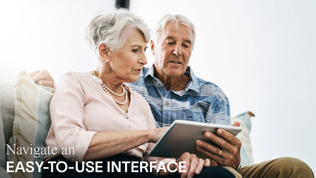 An elderly couple is looking at something on a tablet.