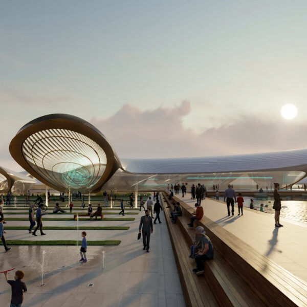 People enjoying time on a sea promenade with a futuristic building in the background, late afternoon.